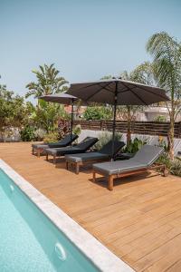 una fila de tumbonas con sombrilla junto a la piscina en Seametry Villa, en La Canea