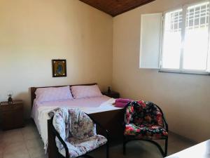 a bedroom with a bed and two chairs at CASA VACANZA PALMENTO BELLA in Santa Maria Del Focallo