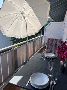 a table with plates and an umbrella on a balcony at Ferienwohnung Flynn in Sonthofen