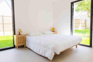 a white bedroom with a bed and a large window at À 490m de la plage, maison neuve pour 8 in Trébérouant