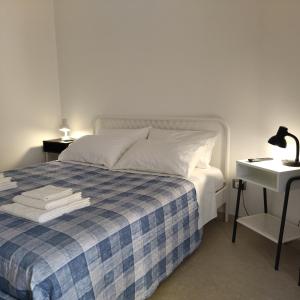 a bed with a blue and white plaid blanket and a table at Putignani 210 Apartment in Bari