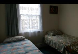 a bedroom with two beds and a window at Inner City Cottage in Gisborne