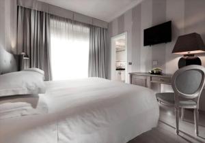 a bedroom with a large white bed and a chair at c-hotels Ambasciatori in Florence