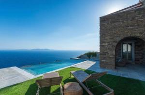 a house with a swimming pool and two chairs at Villa Cybele Tinos in Kardiani