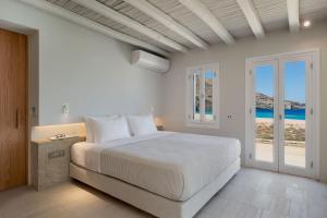 a white bedroom with a bed and a view of the ocean at Ammoa Beach Residences in Vayiá