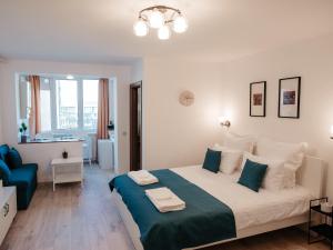 a white bedroom with a large bed and a blue chair at ZARA STUDIO BRASOV in Braşov