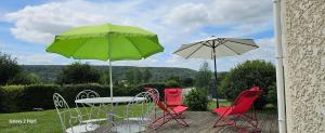 ein Tisch und Stühle mit einem grünen Sonnenschirm in der Unterkunft Comme à la maison in Corneville-sur-Risle