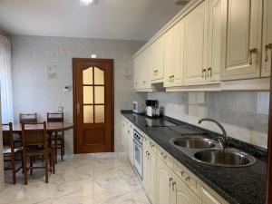 a kitchen with white cabinets and a sink and a table at Casa del Parque in Pereruela +5 photos