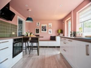a kitchen with pink walls and a wooden floor at Whimsical Haunt in West Malling