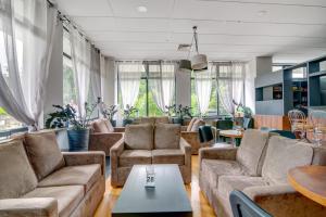 a living room with couches and tables and windows at Silesia Krynica in Krynica Zdrój