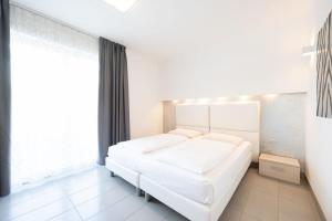 a bedroom with a white bed and a large window at Residence Desiree in Riva del Garda