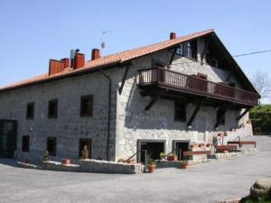 a large stone building with a balcony on top of it at Hotel Antsotegi in Etxebarria