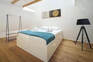 a bedroom with a white bed with a blue blanket at L'Atypique d'Eguisheim in Eguisheim +5 photos