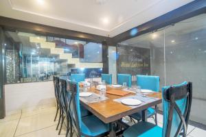 a dining room with a wooden table and blue chairs at Hotel Satyug Inn in Ujjain
