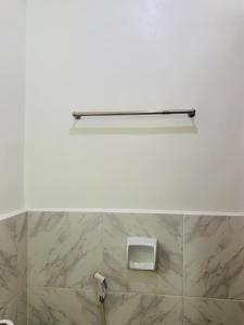 a white tiled bathroom with a soap dispenser on the wall at Francis Dale Lodge L7 in El Nido +8 photos