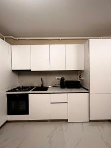 a kitchen with white cabinets and a sink and a stove at Luxury apartament in Mamaia Nord