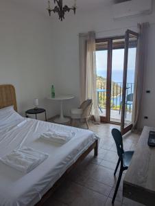 a bedroom with a bed and a table and a balcony at Villa Velta Sea Sunset in Porto Santo Stefano