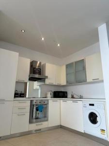 una cocina blanca con una lavadora dentro en Flat in the heart of St Julians, en San Julián 2 fotos más