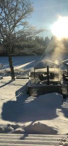 a snow covered park with benches and a tree at Lakehouse med bastu, egen brygga och roddbåt in Målsryd