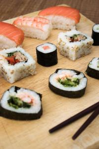 a bunch of sushi on a wooden cutting board with chopsticks at Hyatt Regency Chennai in Chennai