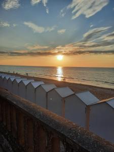 a beach with the sun setting over the ocean at Horizon Marin accès direct plage in Cabourg