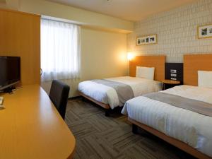 a hotel room with two beds and a desk at Comfort Hotel Nara in Nara