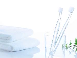 two toothbrushes in a glass next to a stack of towels at Comfort Hotel Nara in Nara