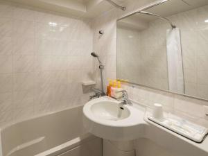 a bathroom with a sink and a tub with a mirror at Comfort Hotel Suzuka in Suzuka +18 photos