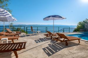 a group of benches and umbrellas next to a swimming pool at Apartments with pool Maraska in Brela