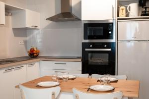 a kitchen with a wooden table and white cabinets at Terres de France Brest in Brest