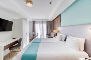 a hotel room with a large bed and a desk at Solana Hotel & Spa in Mellieħa