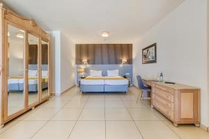 a bedroom with two beds and a dresser and a desk at Solana Hotel & Spa in Mellieħa