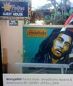 Un cartel de una casa de huéspedes con una pintura de un hombre. en fullesguesthouse, en Gili Trawangan