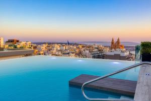 a swimming pool with a view of a city at Solana Hotel & Spa in Mellieħa