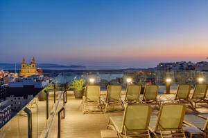 a group of chairs sitting on a balcony at night at Solana Hotel & Spa in Mellieħa