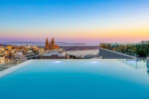a large swimming pool on top of a building with a city at Solana Hotel & Spa in Mellieħa