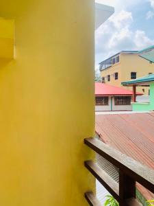 a yellow wall with a wooden railing and a building at Francis Dale Lodge L8 in El Nido