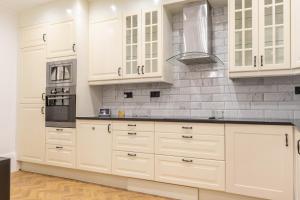 a kitchen with white cabinets and a stove top oven at Kensington Bay View Dreams in London