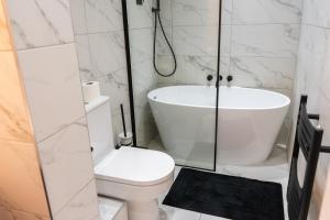 a bathroom with a tub and a toilet and a shower at Kensington Bay View Dreams in London +12 photos