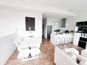 a white living room with a white table and chairs at Luxury 2 Bedroom Apartment with cocktail bar and espresso machine in Auckland