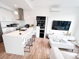 a kitchen with white cabinets and white counter tops at Luxury 2 Bedroom Apartment with cocktail bar and espresso machine in Auckland