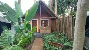 a small house in a garden with a fence at Devocean Eco Adventure Lodge in Ponta do Ouro