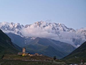 a mountain range with a building in the foreground with a mountain at Guest House Cafe Nita in Ushguli +7 photos