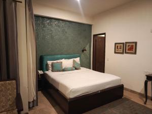 a bedroom with a bed with a green accent wall at Shelton Hotel Johar Town Lahore in Lahore