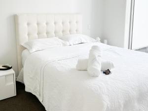 a white bed with white sheets and towels on it at Luxury 2 Bedroom Apartment with cocktail bar and espresso machine in Auckland