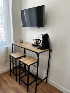 a table with two stools and a television on a wall at L'Emile Zola 2 in Saint-Quentin