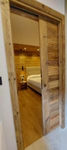 a bedroom with a bed and a wooden wall at Hotel Corona Ferrea in Sappada