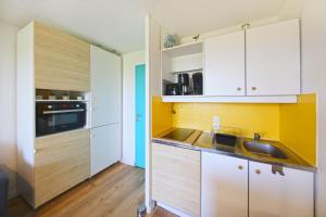 a kitchen with white cabinets and a sink at La Brise de Donville - A 300m de la plage in Donville-les-Bains +7 photos