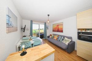 a kitchen and living room with a table and a couch at La Brise de Donville - A 300m de la plage in Donville-les-Bains