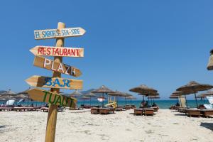 a sign on a beach with chairs and umbrellas at Dadu Rooms in Orikum